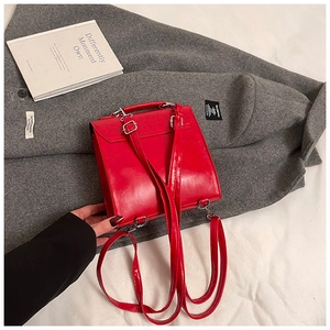 Detailed close-up of glossy red PU leather square bag with silver metal hardware and straps