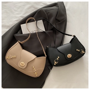 Close-up of vintage leather bags with gold twist-locks and rivets on a grey suit