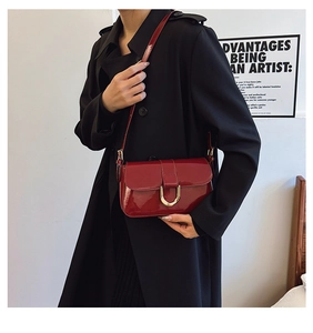 Close-up of vintage burgundy patent leather handbag with gold horseshoe buckle detail