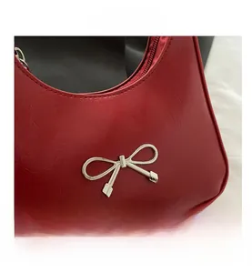 Close-up of a red shiny pleated leather bag with a silver metal bow detail