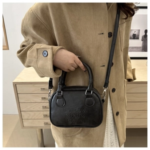 Detail einer schwarzen Mini-Handtasche aus Leder mit lucky OHIO 6mru Prägung und Gurt