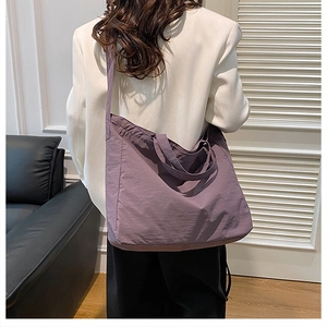 Large purple nylon tote bag styled with a white blazer for a minimalist casual look