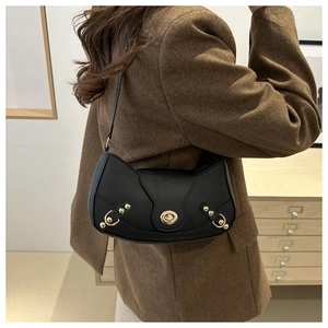 Close-up of black leather half-moon bag featuring gold turn-lock and metallic rivets