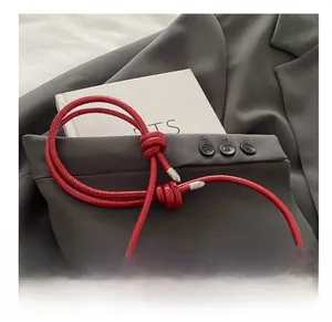 Detail of red leather bag strap with decorative knot and silver hardware tips