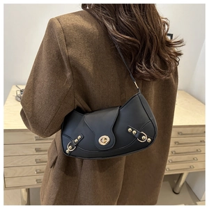 Detail of black underarm bag with gold rivets and hardware lock on a brown coat