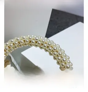 Dettaglio del manico in perle intrecciate e pelle plissettata color crema della borsa