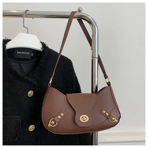 Detailed shot of brown crescent bag with golden lock and rivets on a clothes hanger