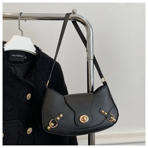 Detail of vintage black leather crescent bag with golden twist-lock and metal rivet accents
