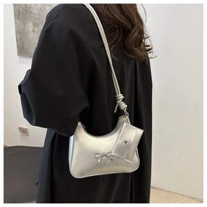 Detail of silver crescent hobo bag with metal bow accent and mini pouch attachment