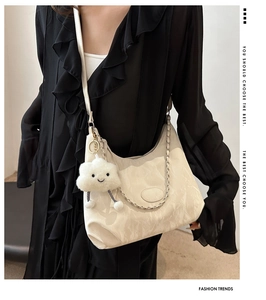 Detail of cream white textured crossbody bag with metal chain and plush cloud charm