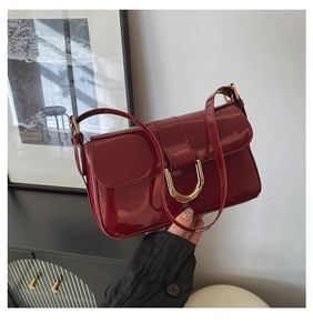 Detail of dark red patent leather shoulder bag with vintage gold horseshoe buckle