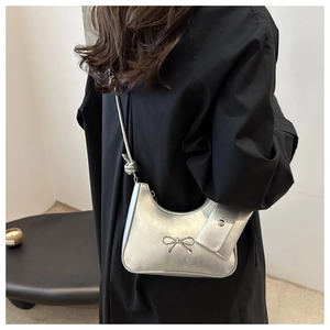 Rear view of model wearing a metallic silver crescent bag with a bow detail and mini pouch
