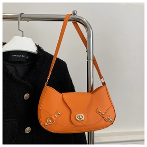 Detail view of bright orange leather underarmpit bag with golden turn-lock and rivet details