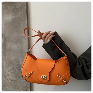 Detail of bright orange faux leather bag with gold buckle hardware and stud accents