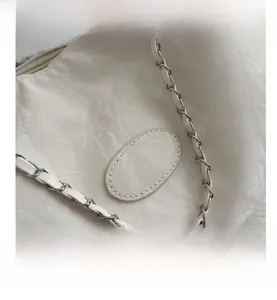 Macro detail of white pleated leather texture and woven silver metal chain strap