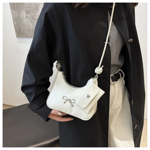 Detail of white PU leather crescent bag with silver bow and mini coin purse attachment