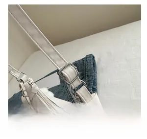 Detail of adjustable silver buckle and metal chain on white leather shoulder bag strap