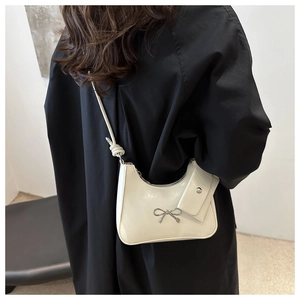Chic bow-knot crescent bag in cream white PU leather worn as a stylish underarm bag