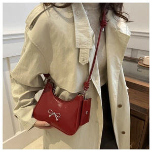 Detail of red patent leather shoulder bag with silver bow and mini coin purse charm