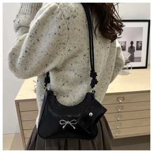 Detail of black crescent hobo bag featuring silver bow accent and detachable mini pouch