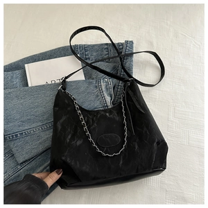 Detail of black crinkled crossbody bag with silver chain decor and shoulder strap