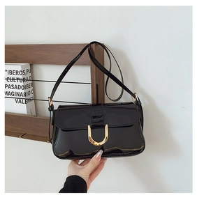 Detail view of the glossy black patent leather surface and golden U-shaped buckle closure