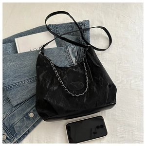 Modern black hobo bag with silver chain and thin strap on a minimalist lifestyle setting