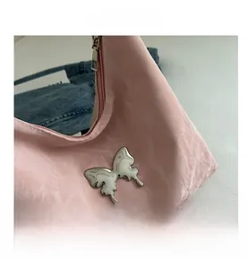 Close-up of pink textured fabric handbag with liquid silver butterfly metal detail