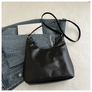 Detail of silver chain strap woven with leather on a stylish black shoulder bag
