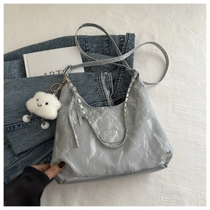 Detail of light gray shoulder bag with metallic chain and white cloud plush pendant accessory