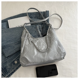 Close-up of silver crescent hobo bag featuring crinkled texture and metallic chain detail