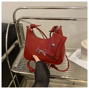 Detail of red crescent bag with silver bow accent and matching mini pouch accessory