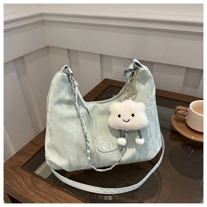 Detail of mint green pleated shoulder bag featuring a white plush cloud charm and metal chain