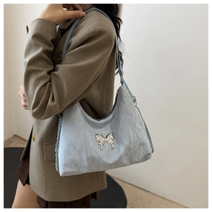 Close-up of light blue cloud-textured shoulder bag featuring a silver butterfly buckle