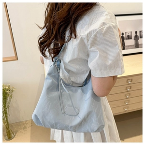 Detailed view of light blue hobo bag with pleated texture and stylish oval patch