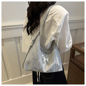 Detail of silver metallic pleated hobo bag featuring a mirror butterfly metal accessory
