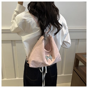Detail of pink half-moon crossbody bag with silver butterfly charm on white shirt