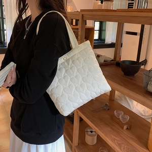 White quilted tote bag with heart patterns shown in a cozy indoor lifestyle setting