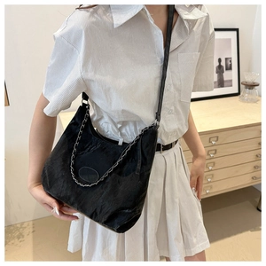 Detail of black crossbody bag featuring soft leather texture and silver chain strap
