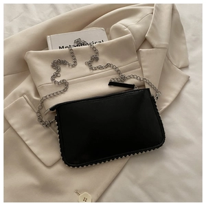 Detail of black rectangular shoulder bag with silver studs and thin chain strap