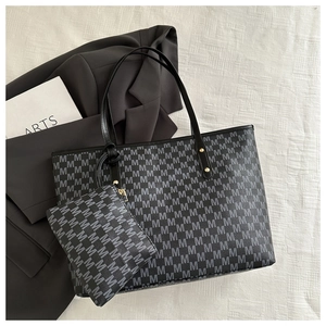 Flat lay of black jacquard tote bag with repetitive M pattern and matching zipper pouch