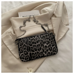 Close-up of leopard print shoulder bag with silver studs and metal chain strap detail