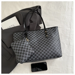Detail shot of the M-patterned tote bag with matching pouch and sleek gold hardware