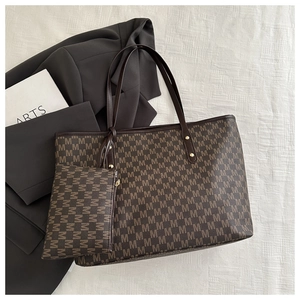 Detail view of large brown M-pattern tote bag set with matching pouch on office desk