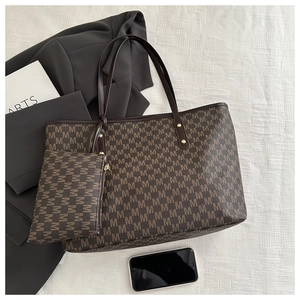 Detail of dark brown tote bag set with M-letter print and gold hardware rivets