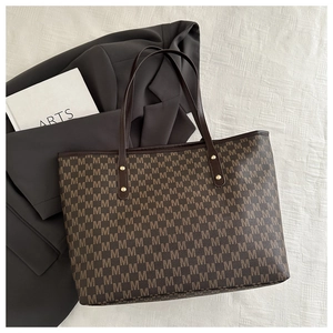 Detail view of large tote bag with brown monogram pattern and golden metal rivets