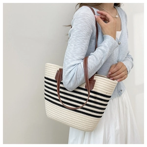 Close-up of woven tote bag with black stripes and brown leather shoulder straps