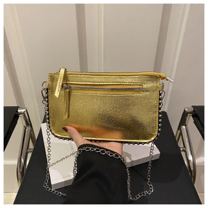 Detail of gold metallic crossbody bag featuring silver stud trim and sleek chain strap