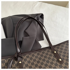 Top-down view of large tote bag with M-pattern print and gold stud strap detail