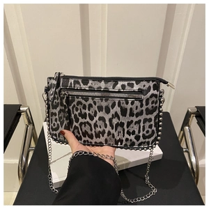 Detail of leopard print crossbody bag with silver studs and chain strap held in hand